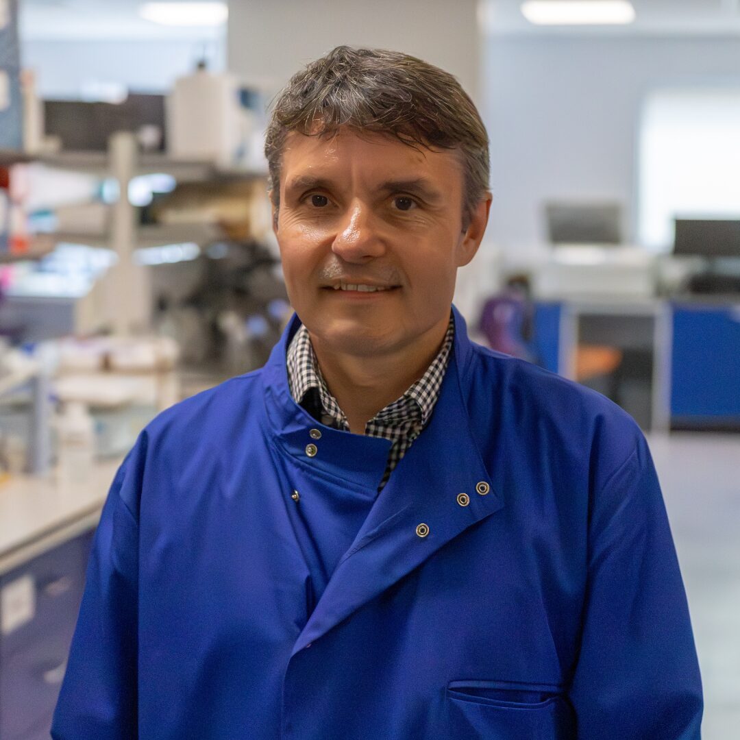 Image of Professor Mark Cragg in a bright blue lab coat.